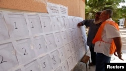 2014年6月25日，首都的黎波里一位官员协助选民校内投票前寻找自己的名字