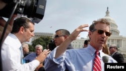 两名共和党籍参议员特德•克鲁兹（左）和兰德•保罗（右）赶到国会山西侧草坪参加反奥巴马医保集会时对媒体讲话。（2013年9月10日）