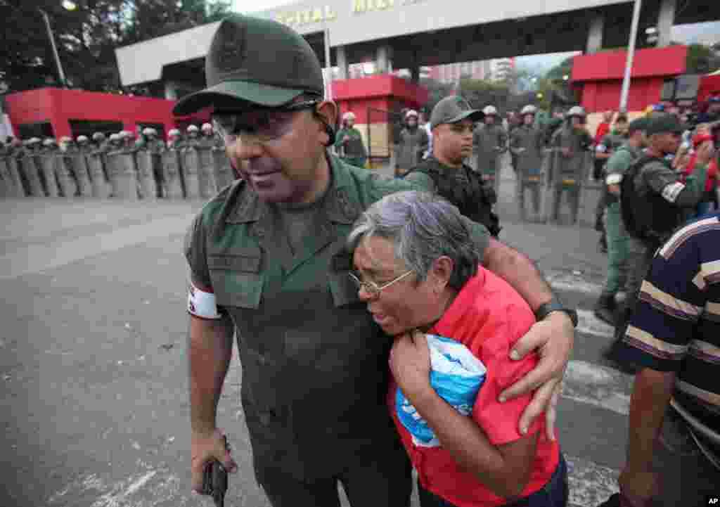 一名军官2013年3月5日在委内瑞拉加拉加斯的军医院外面安慰一名查韦斯的支持者。