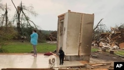 Amber Phillips stands outside the family's safe room, located on their property in Moss, Miss., following a tornado, April 13, 2020. 
