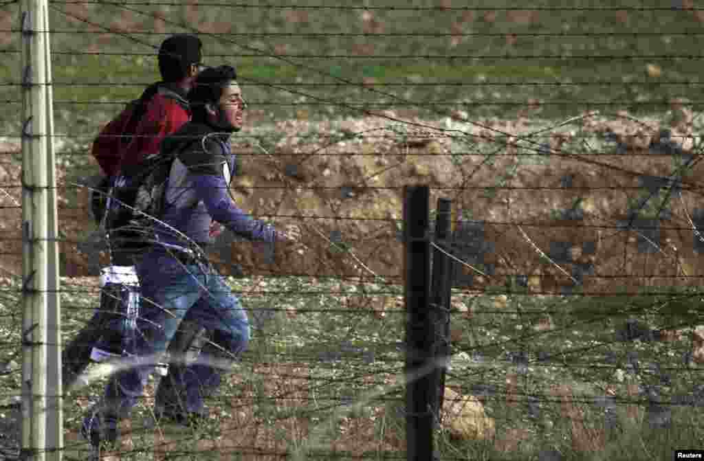 Syrian refugees in the northern Syrian town Ras al-Ain run to cross the border fence into Turkey during gunfire, as seen from Turkey's Sanliurfa province, November 22, 2012.