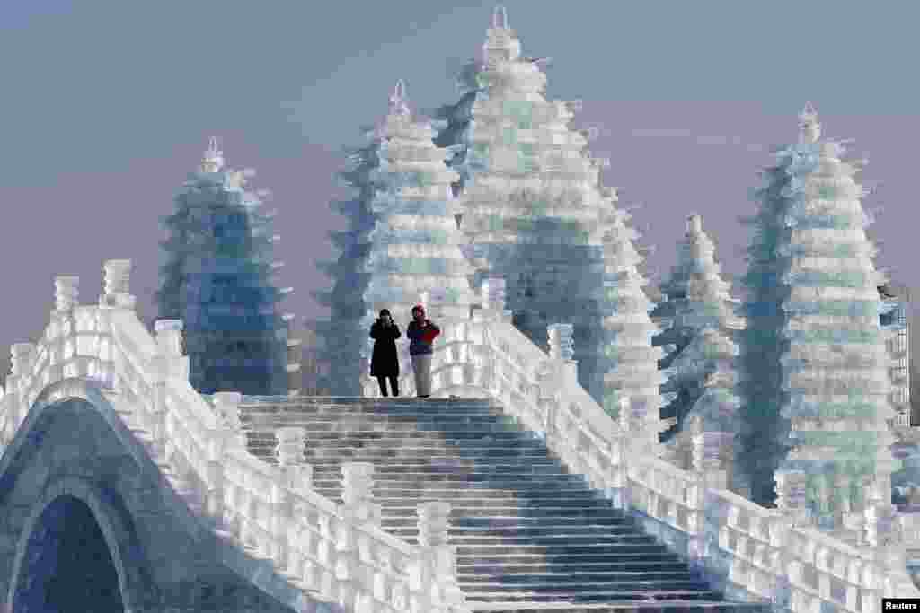 在中国东北黑龙江省的哈尔滨国际冰雪节期间，游客走在冰雕桥栏和塔楼之间（2019年1月7日）。哈尔滨简称哈市，别名冰城、東方莫斯科、东方小巴黎。