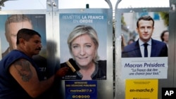 Campaign posters of French National Front (FN) political party leader Marine Le Pen (C) and head of the political movement En Marche! (Onwards!) Emmanuel Macron (R), are seen in Antibes, France, April 14, 2017.