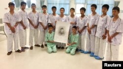 The 12-member "Wild Boars" soccer team and their coach rescued from a flooded cave pose with a drawing picture of Samarn Kunan, a former Thai navy diver who died working to rescue them at the Chiang Rai Prachanukroh Hospital, in Chiang Rai, Thailand, July